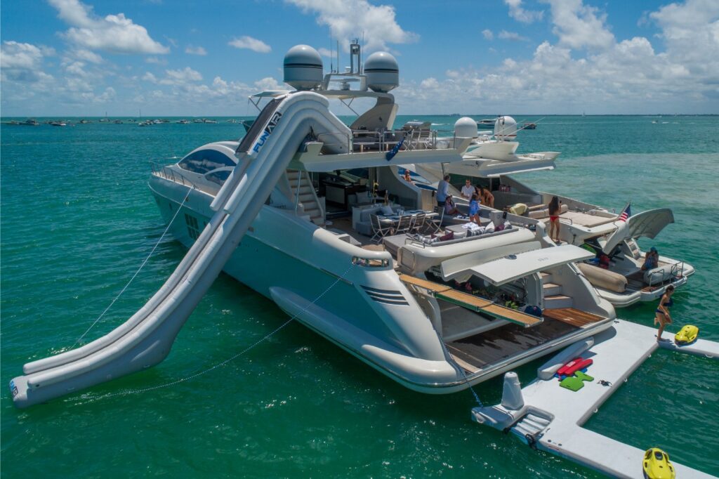 A yacht with a large inflatable slide extending from its deck into the water